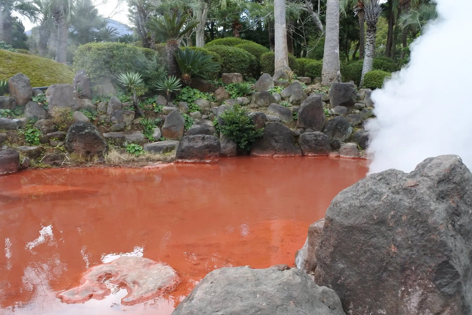 Chinoike Jigoku, a rust-red pond with white steam rising from it