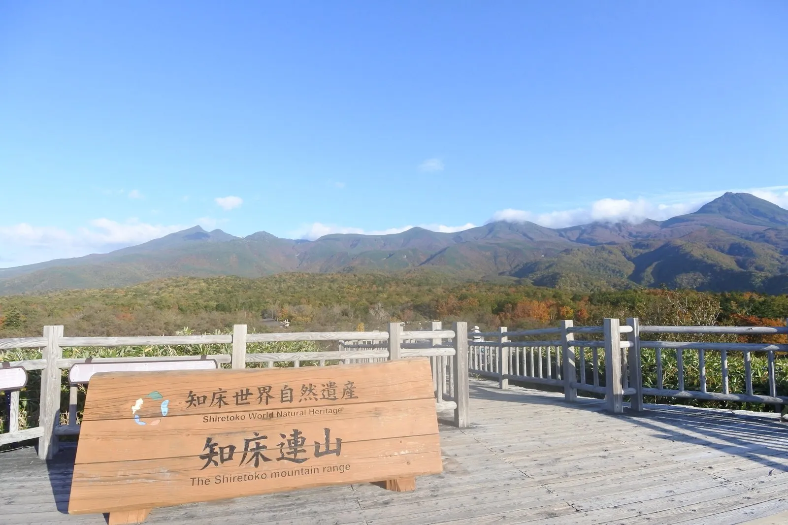 知床五湖の高架木道。「知床世界自然遺産/知床連山 The Shiretoko mountain range」の木製看板と、その奥に連なる知床連山