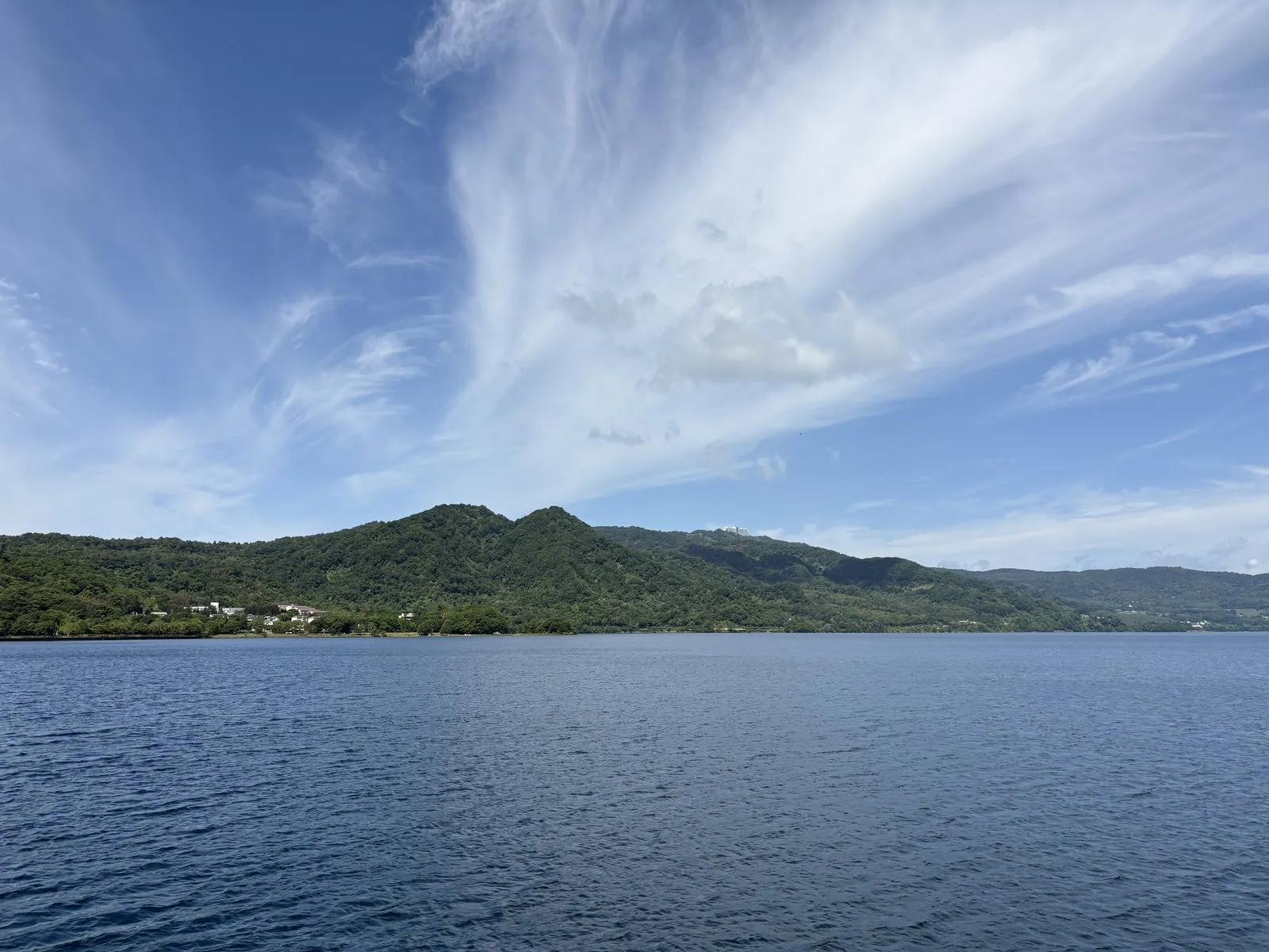 好天の洞爺湖クルーズ。青い湖面の向こうに、緑に覆われた中島が浮かぶ